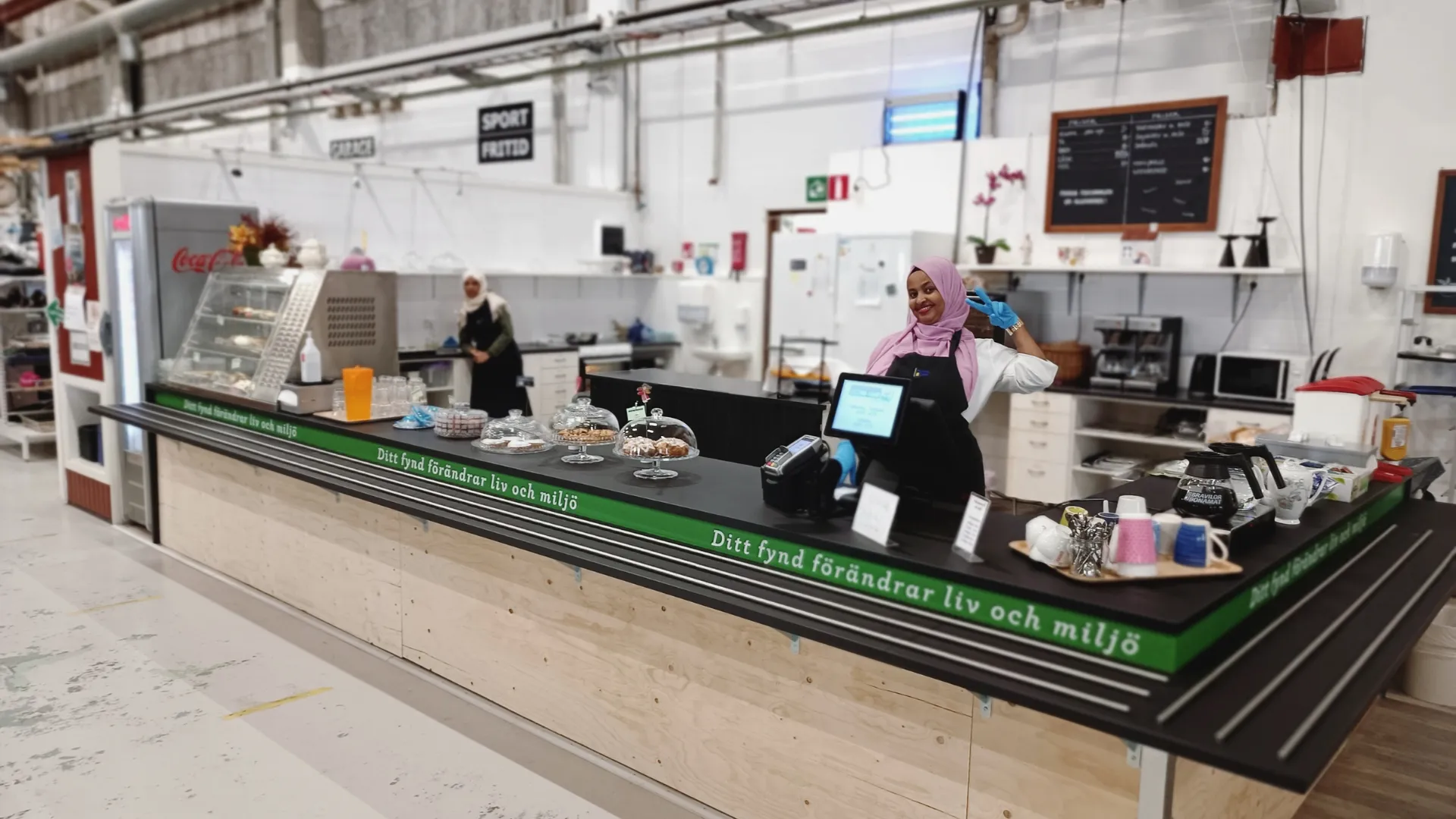 Weaving macrame at home Makrame gjort av vitt garn fäst i en brun gren ligger på ett brunt träunderlag. Brevid finns tre rullar med vitt garn