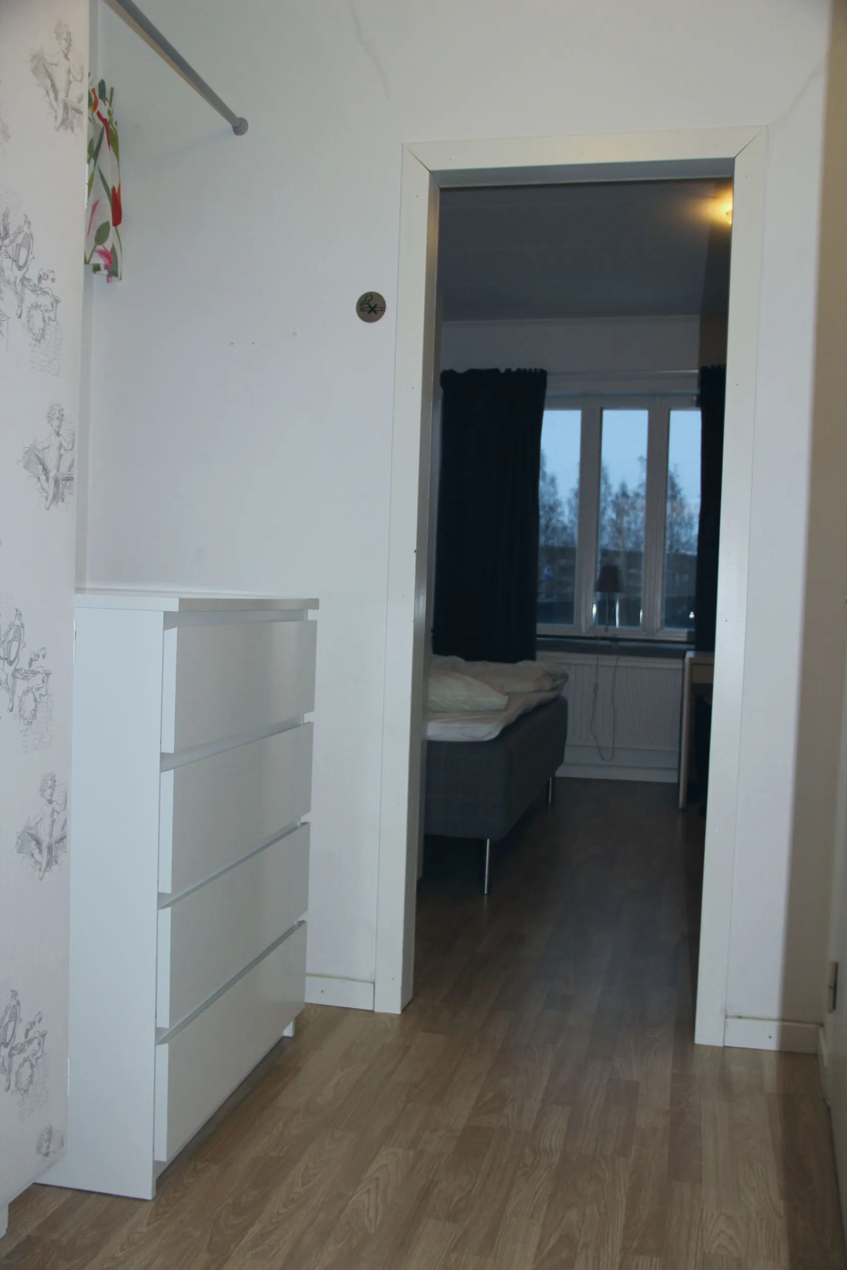 En hall med en vit byrå. I bakgrunden ser man in i sovrummet